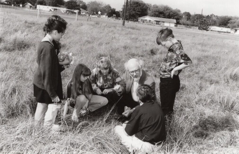 Photograph of students from Baker Junior High School outside being taught about the natural world by an unidentified instructor at a fractal conservation program established as part of the University of Houston-Clear Lake and Environmental Institute of Houston collaboration for environmental education. The program was conducted in the 1994-1995 school year.â€¯